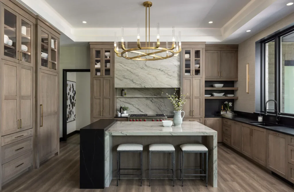 A kitchen with light brown cabinets and a white waterfall island with 3 white stools.