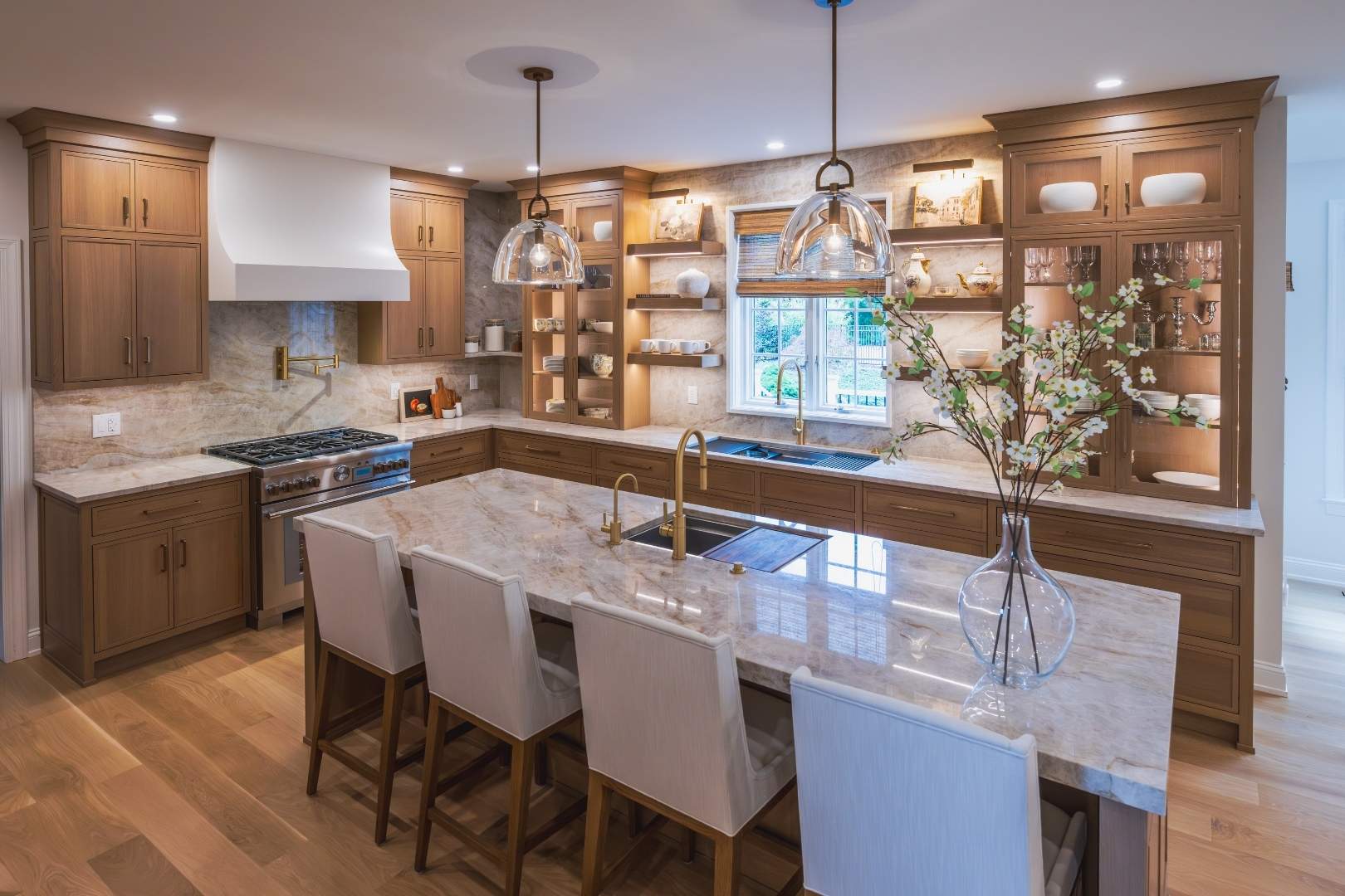 A kitchen remodel by Laslo with oak lighted cabinets and a large white island with 4 barstools.